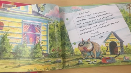 An open page of an illustrated children's book, a picture of a dog in a backyard and a handwritten note.