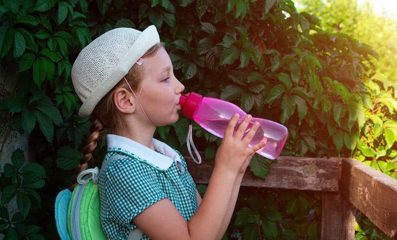 Image of a school girl drinking water from a bottle