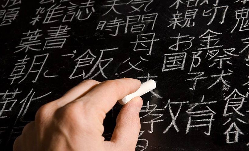 Teacher writing a lesson in Japanese on the blackboard