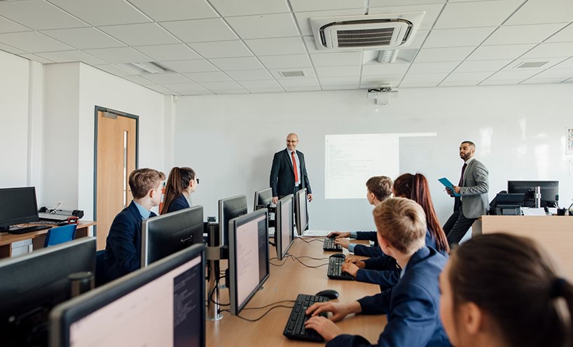 A group of people sitting in an office working together using computers.