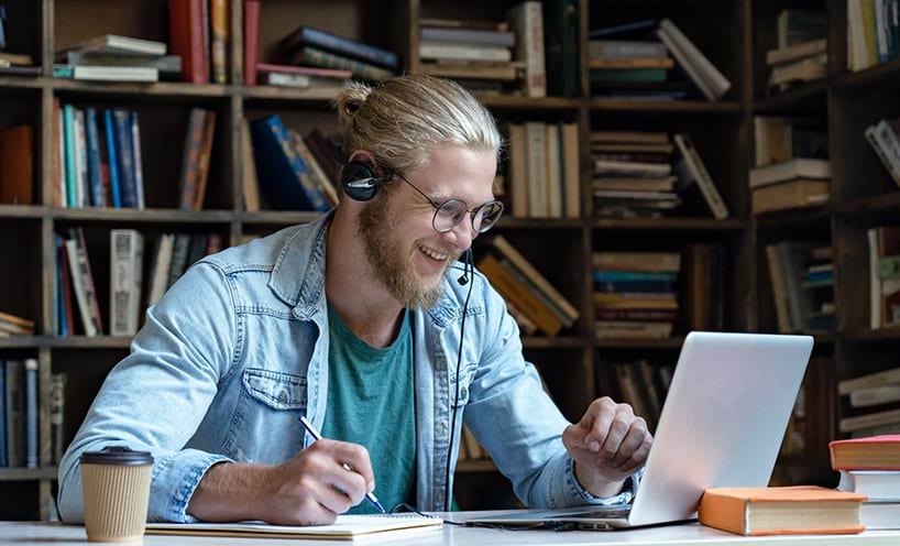 A man wearing headphones working on his laptop.