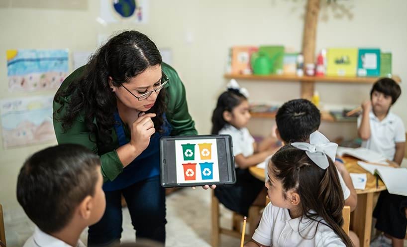 A teacher is showing a picture of bins to some students in the classroom.