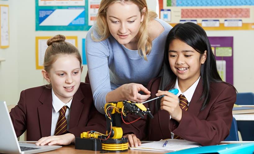 A teacher and some students working on a science project in a classroom.