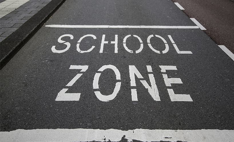 Image of the road. The words school zone are painted on the cement.