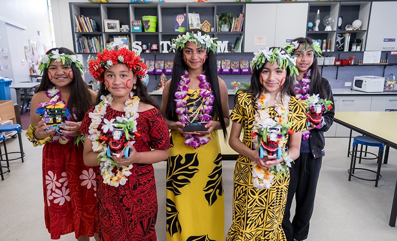 The Poly Girls team smile at the camera and hold their robotics in hand.