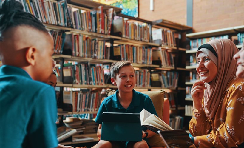 A group pf students and their teacher sitting together in the library.